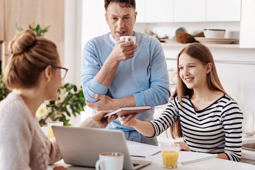Niña con sus padres en la cocina con una buena actitud tras su educación mediante el refuerzo positivo y negativo.
