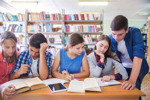 Adolescentes en la biblioteca estudiando con una gran motivación escolar.