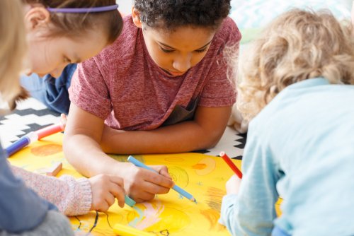 Niños trabajando en grupo a los que han hecho una foto para publicar en el periódico del colegio.