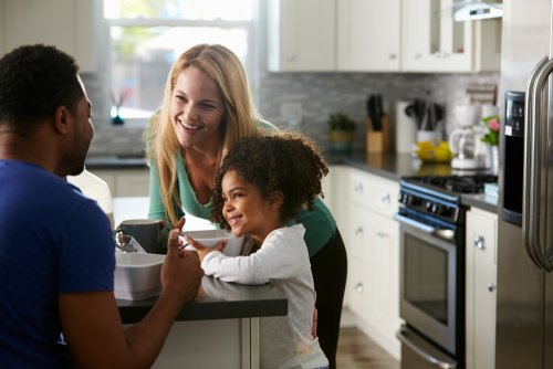 Familia en la cocina de casa hablando sobre criar a niños biculturales con su hija.