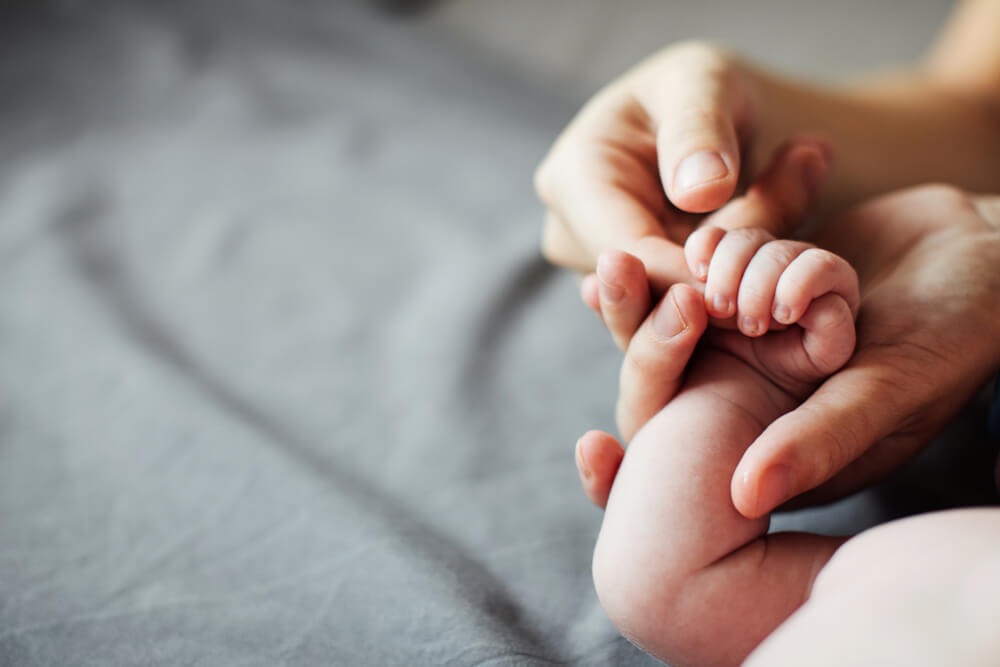 Bebé agarrando el dedo de sus padres.