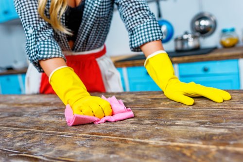 Mujer limpiando la cocina como parte del trabajo doméstico.