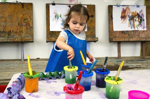 Niña pintando cuadros para desarrollar su talento artístico en preescolar.