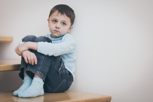 Niño sentado en una escalera con pensamientos intrusivos.