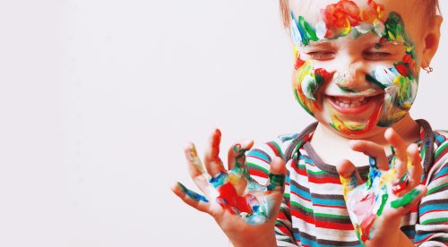 Niño con las manos y la cara llenas de pintura.