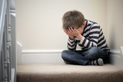 Niño sentado en las escaleras de su casa muy triste porque no saber cómo gestionar la decepción que siente con sus amigos.
