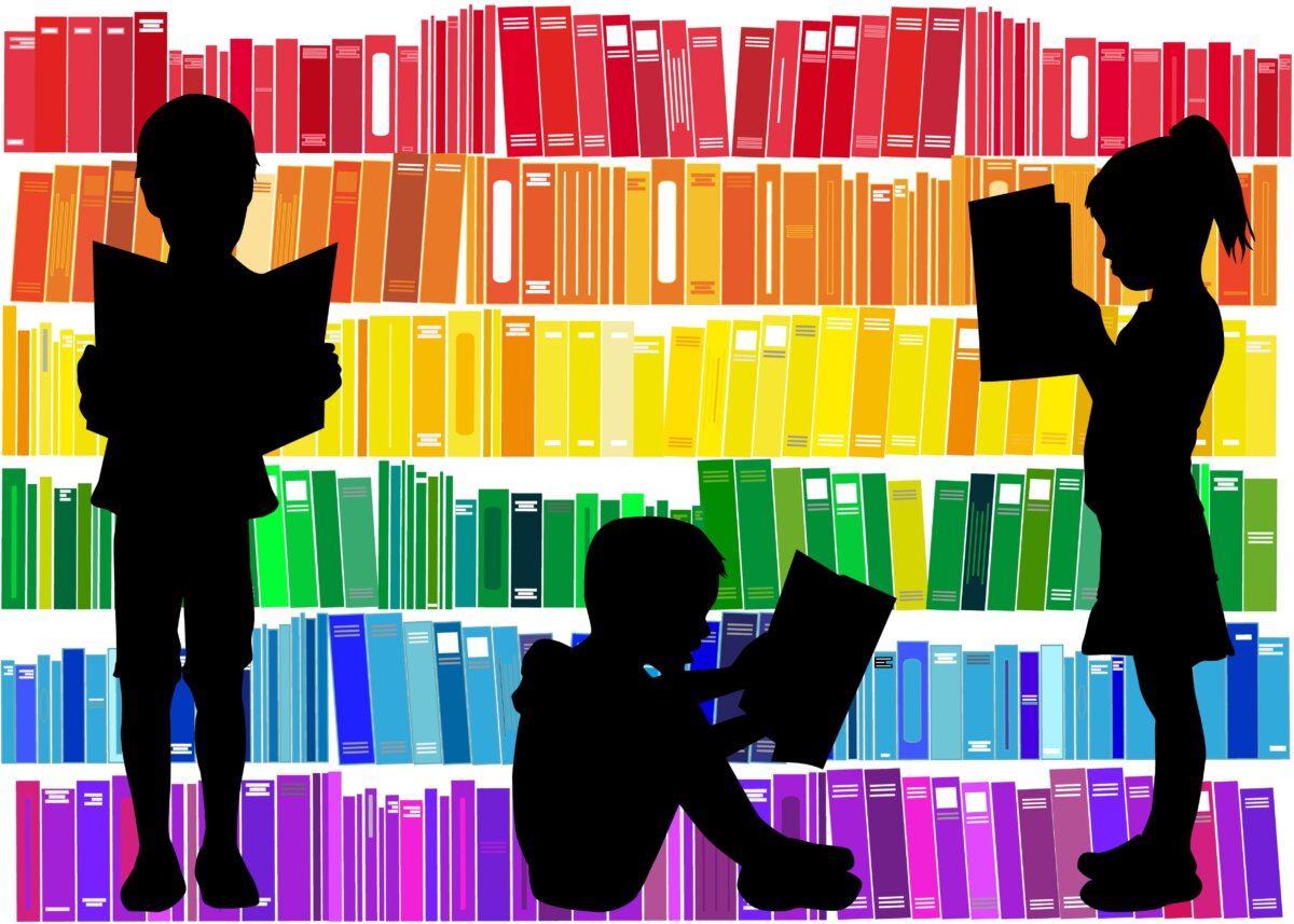 Niños leyendo libros escogidos de una librería ordenada por colores.