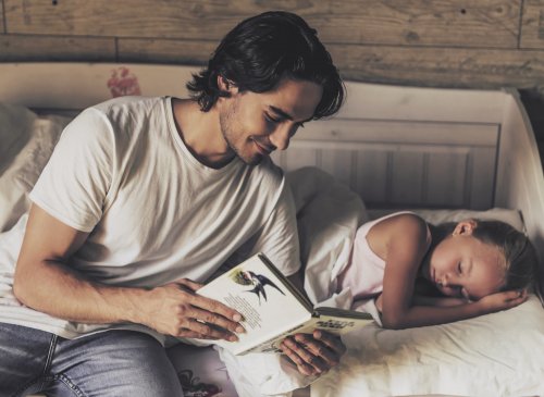 Padre leyendo un cuento a su hija para fomentar el hábito de irse a dormir a una hora concreta.