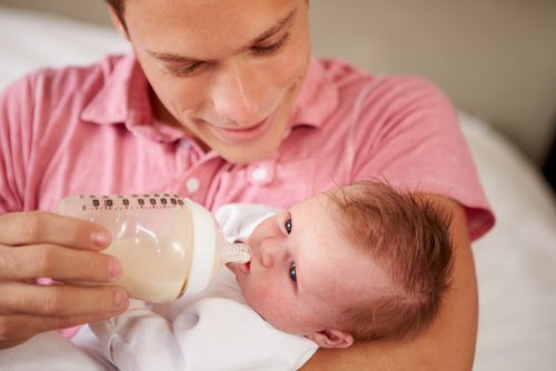 Papá dándole el biberón de leche materna pasteurizada a su bebé.