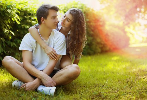 Pareja adolescente dándose un abrazo en el parque.