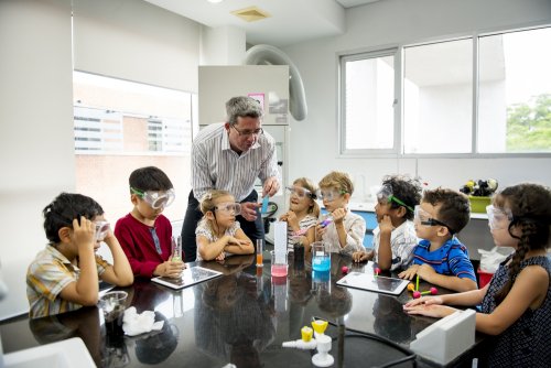 Niños en clase de química con su profesor utilizando una metodología de aprendizaje basado en proyectos.