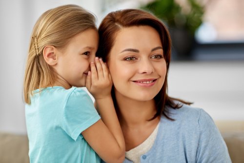 Madre escuchando lo que le dice su hija al oído sobre una experiencia con personas tóxicas.