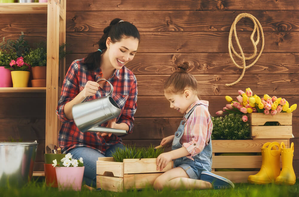 Madre con su hija regando algunas plantas del jardín,