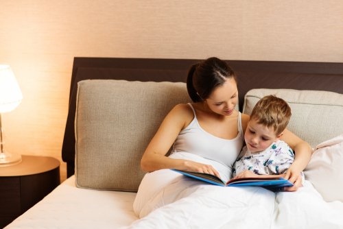 Madre leyendo un cuento a su hijo en la cama para introducirlo en el mundo de la lectura.