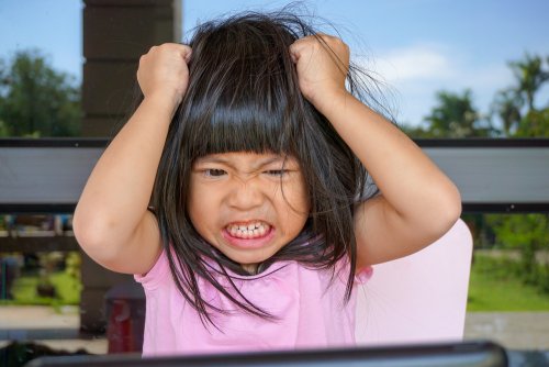 Niña enfadad tirándose del pelo.