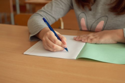 Une jeune fille qui écrit sur un cahier.