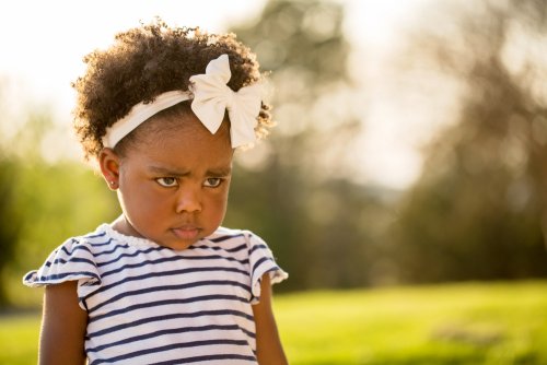 Niña de dos años en la etapa del no muy seria en un parque.