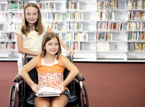 Niña en la biblioteca acompañando a su hermana con discapacidad.