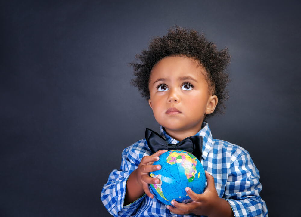 Niño con una bola del mundo en las manos.