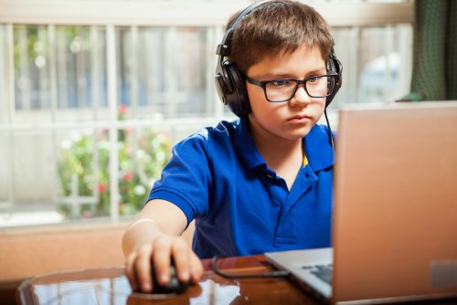 Niño jugando con el ordenador con el consentimiento de sus padres tras informarse sobre cómo deben usar los niños las tecnologías.