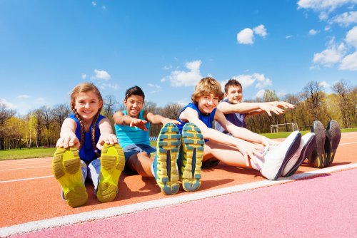 Niños haciendo estiramientos en atletismo como parte del entrenamiento y de los valores que transmite el libro Prohibido gritar.