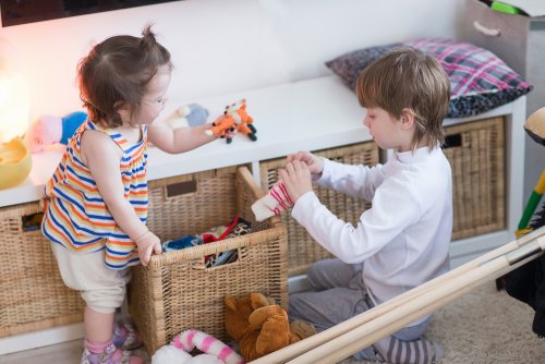 Niños recogiendo sus juguetes, una de las tareas sencillas que pueden realizar en casa.