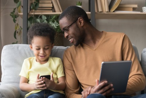 Padre con su hijo usando eBiblio App en casa durante la cuarentena.