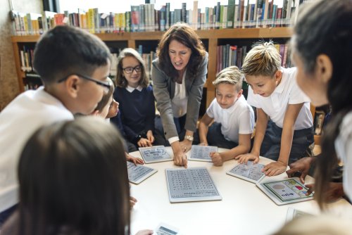 Profesora trabajando con sus alumnos en la biblioteca escolar con tablets.