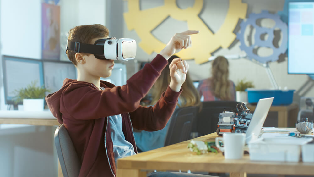 Alumno utilizando las gafas de realidad virtual y aumentada en el aula para aprender.