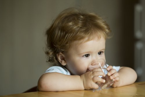 Bebé bebiendo agua de un vaso.