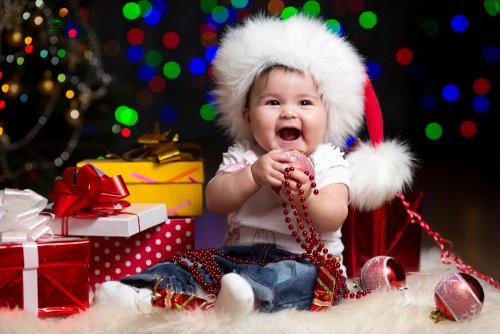 Bebé rodeado de todos sus regalos de Navidad.