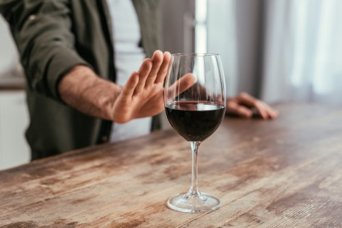 Homme refusant un verre de vin.