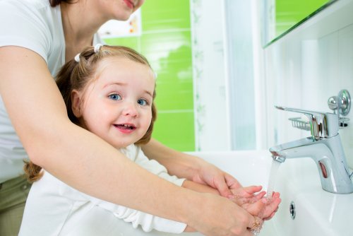 Madre e hija lavándose las manos para fomentar hábitos.