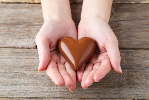 Manos sosteniendo un corazón de chocolate.