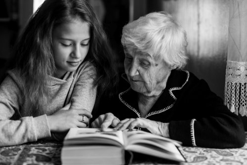 Niña leyendo frases de Jean Piaget con su abuela.