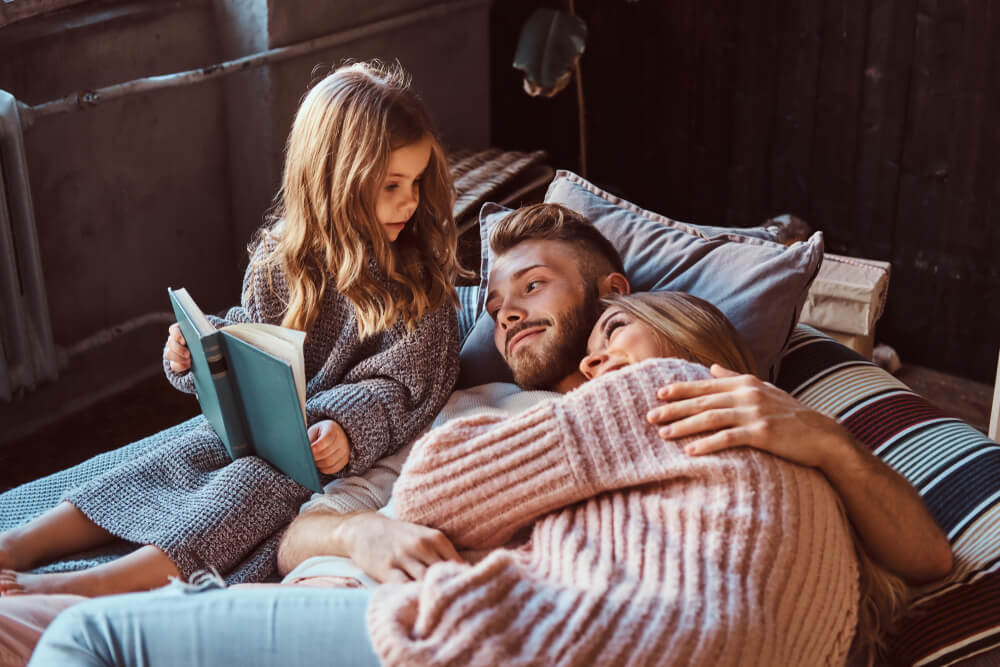 Niña leyendo un cuento a sus padres.