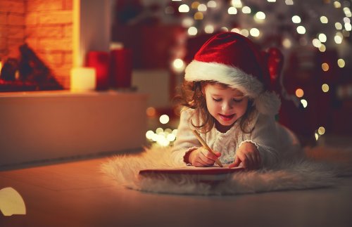 Niña escribiendo la carta a Papá Noel y los Reyes magos después de haber visto con sus padres el corto Una carta más corta.