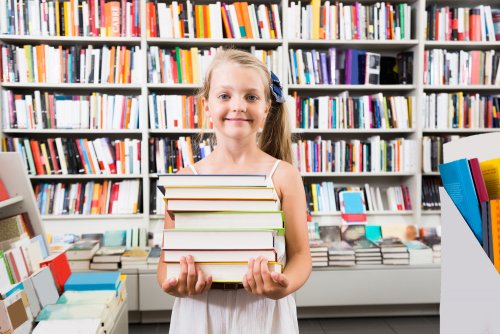 Niñas cogiendo libros de la biblioteca escolar.