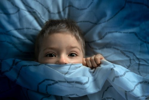 Niño metido en la cama con miedo al irse a dormir.