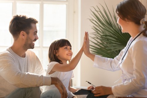 Niña chocando la mano con su pediatra tras una revisión.