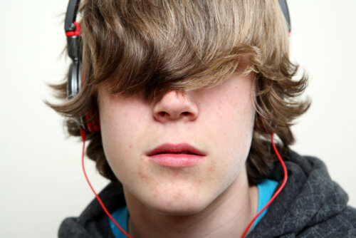A teenage boy with his hair covering his eyes, wearing headphones.
