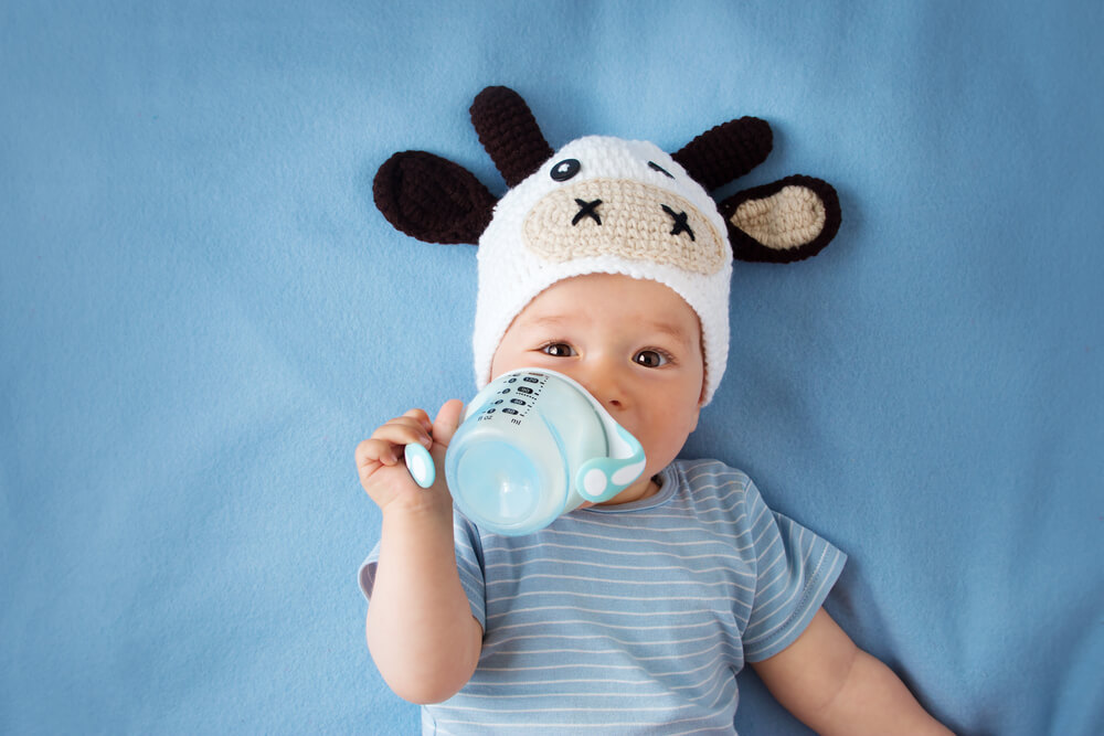 En baby som dricker modersmjölksersättning från en sippy cup.