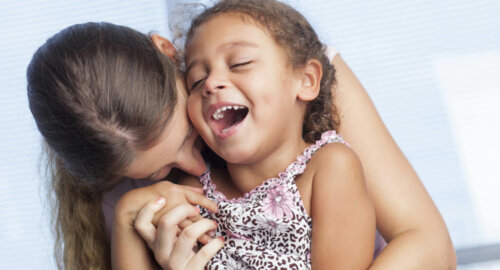 Madre abrazando y haciendo reír a su hija.