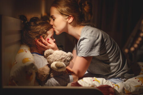 Madre dando un beso de buenas noches a su hija.