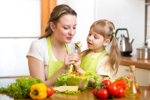 Madre enseñando a su hija a alimentarse de manera saludable como una de las habilidades de la vida para enseñar a los niños.