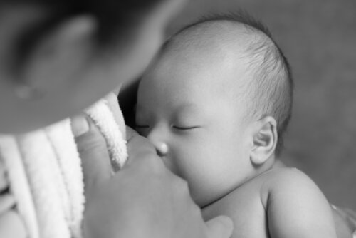 Mamá dando el pecho a su bebé durante la lactancia para proveerle de las defensinas de la leche materna.