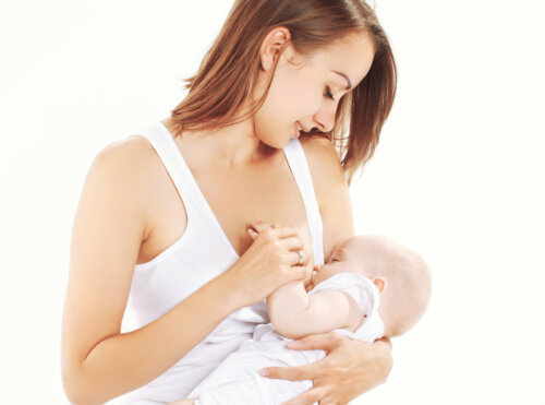 Madre dando el pecho a su bebé durante la lactancia y llevando a cabo una crianza natural.