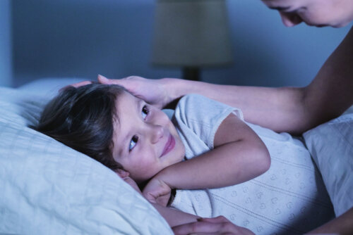 Madre dando un beso de buenas noches a su hija antes de contarle algunas curiosidades sobre el sueño infantil.