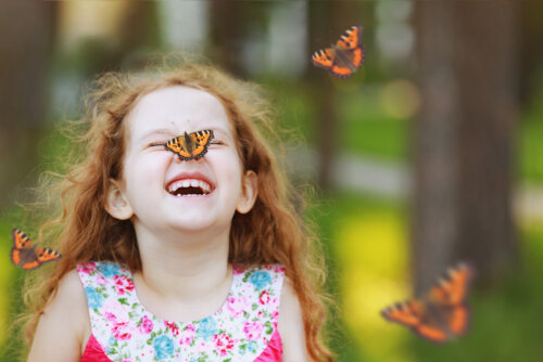 Niña con una mariposa posada en su nariz.