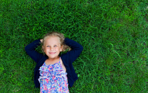 Niña relajada tumbada en el césped para después aplicar la técnica del anclaje.
